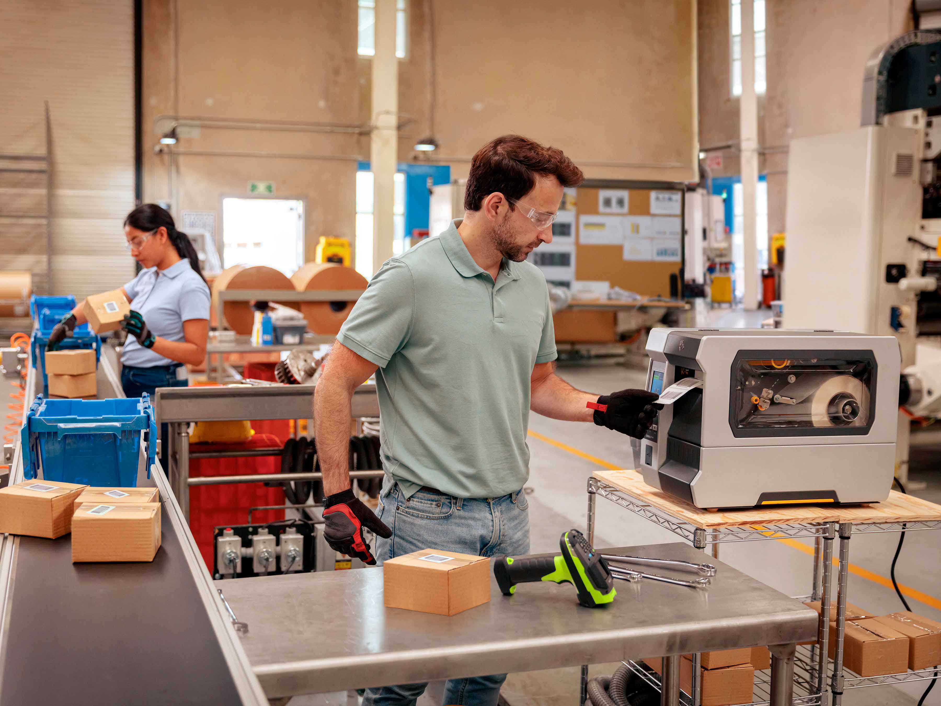 Zebra mobile printer attached to a belt strap prints labels and receipts in a warehouse while worker enters information on a handheld computer